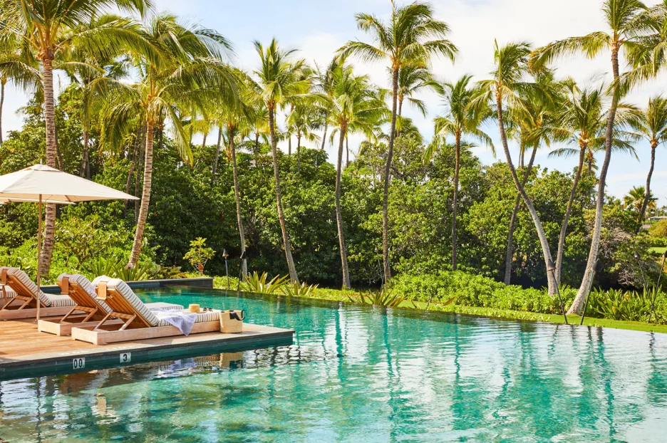 a pool deck with chairs and palm trees