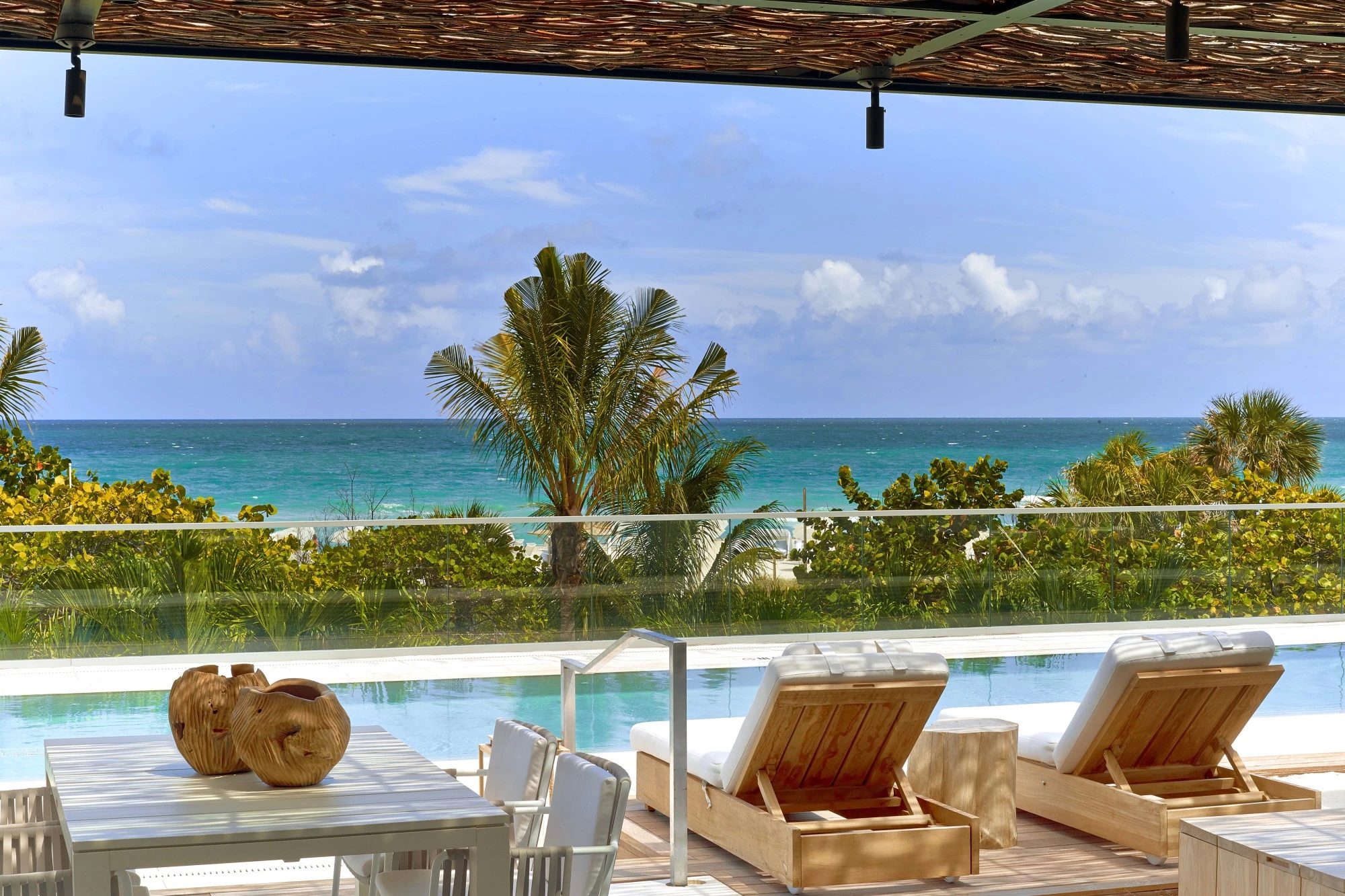 Pool chairs overlooking pool with beach in background